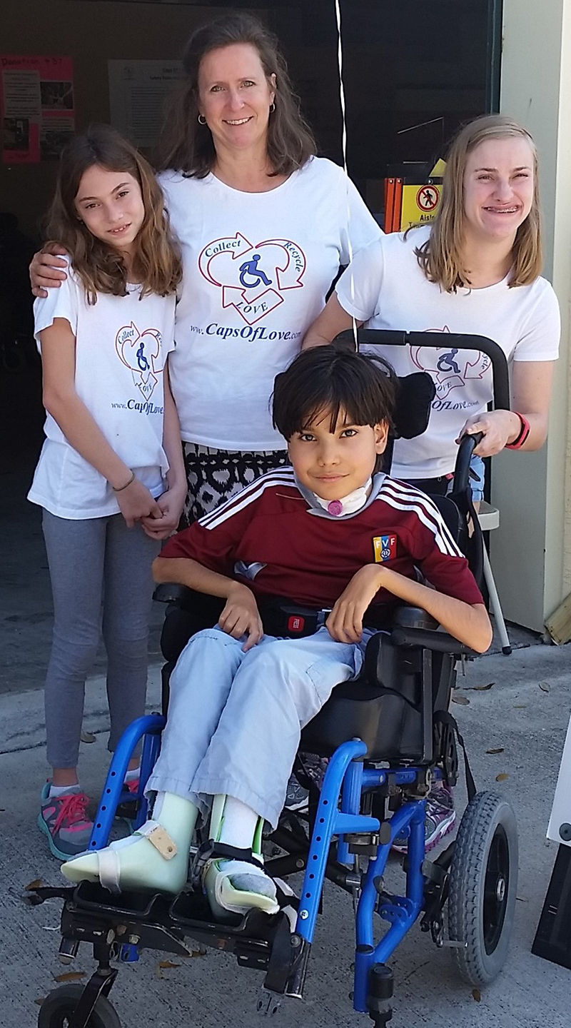 woman, two young girls, and a boy in a blue wheelchair